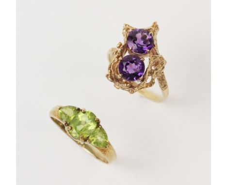 A 9ct gold dress ring, comprising two round brilliant cut purple amethyst coloured stones, each 7mm diameter, claw set to an 