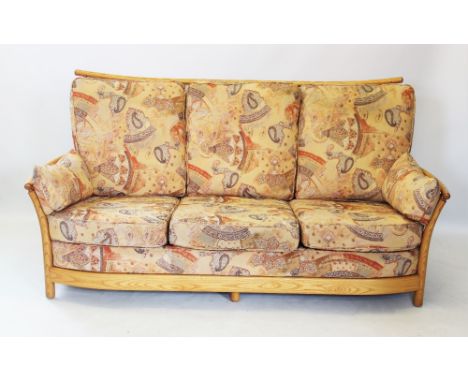 An Ercol blonde ash 'Renaissance' three piece lounge suite, comprising a three seater settee with curved lath back, flanked b