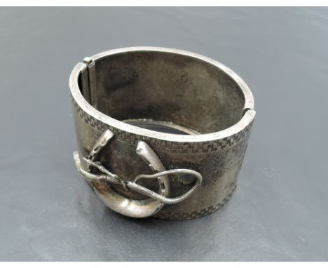 A Victorian white metal hinged cuff bangle stamped Sterling of equine interest with applique horse shoe and riding crop decor