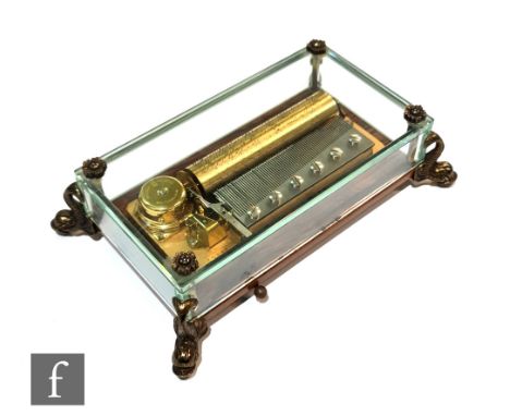 A post 1950s Swiss Reuge musical box seated in a glass case, playing three airs, William Tell, The Barber of Seville and The 