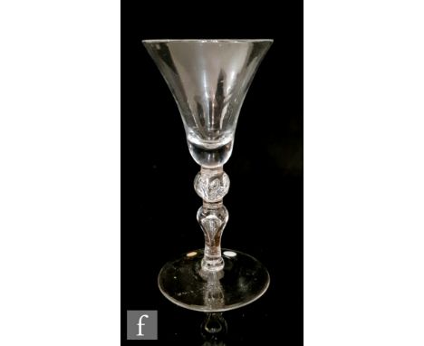 An 18th Century Newcastle style light baluster drinking glass circa 1750, the heavy based bell form bowl above a beaded spher