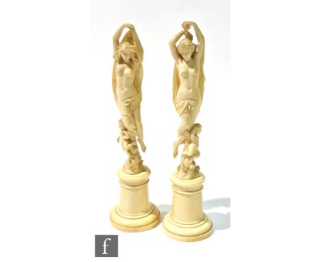 A pair of late 19th Century French carved ivory figures of a pair of semi naked classical dancing figures, each holding a clo