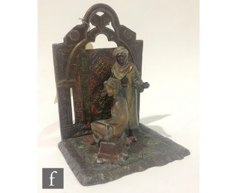 A 20th Century Austrian painted spelter bookend of an Arabian carpet seller and a seated semi-naked female, height 15cm. 