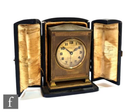 A small Edwardian gilt bedside clock by W Greenwood &amp; Sons Leeds, eight day movement with alarm in blue leather case, hei