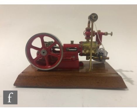 A Stuart single cylinder horizontal engine, painted red with six spoked flywheel, raised to a mahogany plinth, height 15cm, w