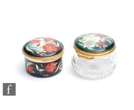 Two Moorcroft Enamel trinket boxes, the first decorated with red flowers, the second with purple and white flowers with a cut