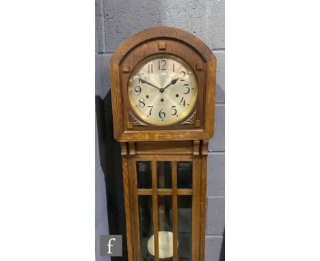 An early 20th Century oak Grandmother clock, the arched topped case with bevel-cut glass panels enclosing a silvered dial wit