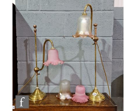 A pair of Edwardian scroll arm brass table lamps, each with an amber and pink crimped edge shade, two spare shades and a mode