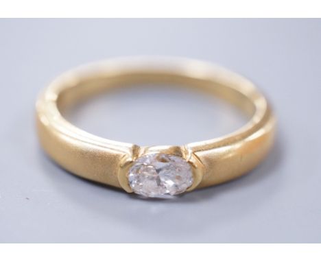 A modern 18ct gold and oval cut solitaire diamond set ring, with sandblasted shank, size K, gross weight 4 grams, the diamond