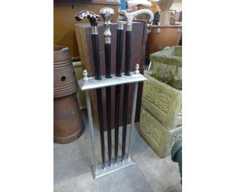 A chrome stick stand and four walking sticks 