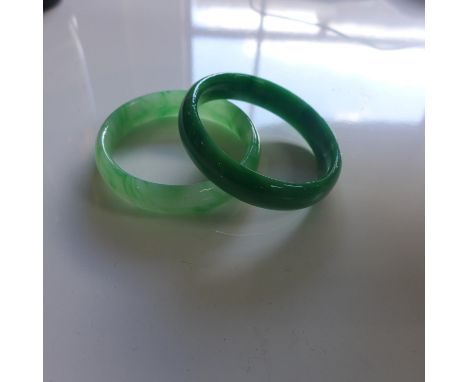 Two Chinese green jade bangles one in a paler shade of green, dia; 7cm and a darker shade of green, dia: 7cm 