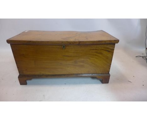 A 19th century oak trunk with wrought iron side handles raised on bracket feet and with hinged lid, H: 47.5 x W: 94 x D: 43.5
