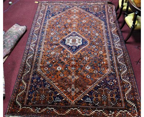 A Southwest Persian Qashqai carpet with central diamond medallion with repeating animal motifs and petal motifs on a terracot