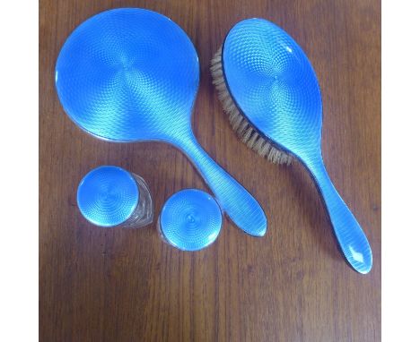 An early 20th century sterling silver and blue guilloche enamel dressing set comprising of a hand mirror, hairbrush, and two 