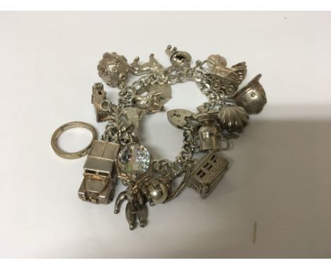 A silver charm bracelet with numerous charms and a silver ring total weight 89g