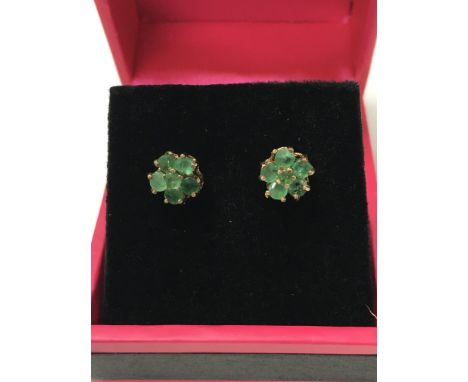 A pair of 9ct gold stud earrings set with a cluster of emeralds in the shape of a flower.