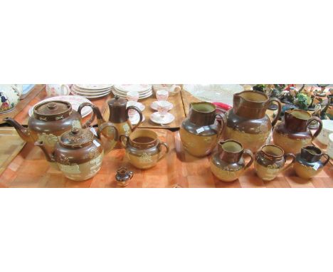 Two trays of two-tone, relief decorated, salt glazed, mostly Doulton Lambeth pottery to include: seven jugs of various sizes,