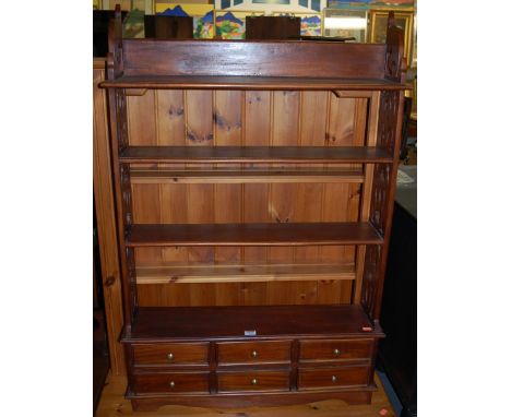 A reproduction hardwood four-tier hanging wall shelf, having pierced sides over six short lower drawers, width 75cm