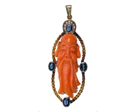 14k White and Yellow Gold and Coral Pendant  Having a 40mm by 10mm carved coral face flanked by oval cut blue sapphires, top 