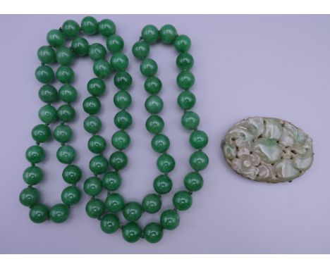 A string of apple green jade beads and a vintage carved jade brooch with silver mount stamped, silver - China. The former app