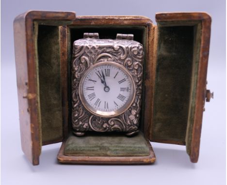 A silver cased carriage clock, housed in a leather travelling case. The case 10 cm high.