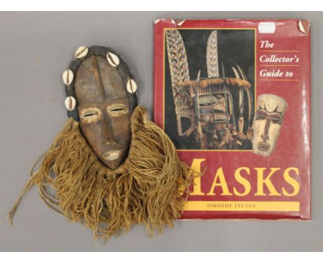 A tribal mask and a Collector's Guide to Masks book. The former 30 cm high.