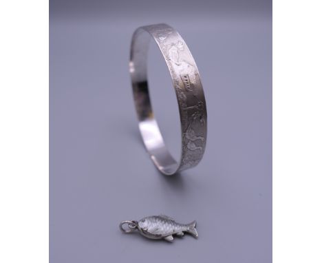 A silver bangle decorated with nursery rhyme animals and a silver enamel fish form charm. The former 6.5 cm diameter.