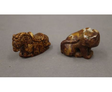 A mottled soapstone carving of a seated cat with inlaid eyes and a Chinese russet jade carving of a recumbent horse. The latt