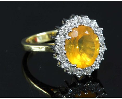 An 18ct gold fire opal and diamond cluster ring, with an oval mixed cut fire opal, claw set to a border of brilliant cut diam