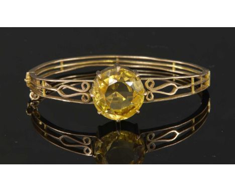 A late Victorian single stone citrine bangle, of oval hinged form. A circular mixed cut citrine, claw set to a plain collet w