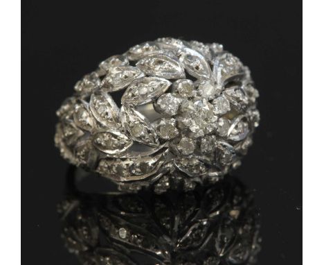 A white gold diamond bombé ring, with a brilliant cut diamond, six claw set to the centre to a border of smaller brilliant cu