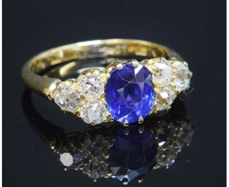 A late Victorian sapphire and diamond ring , with an oval mixed cut sapphire, claw set to the centre. A trefoil cluster of ol