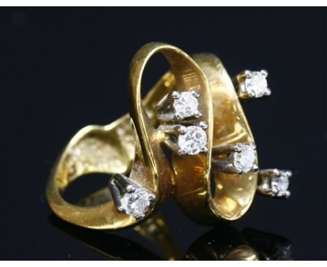 A gold diamond set wave head ring, c.1970, with a looped flat wire head and scattered brilliant cut diamonds all four claw se