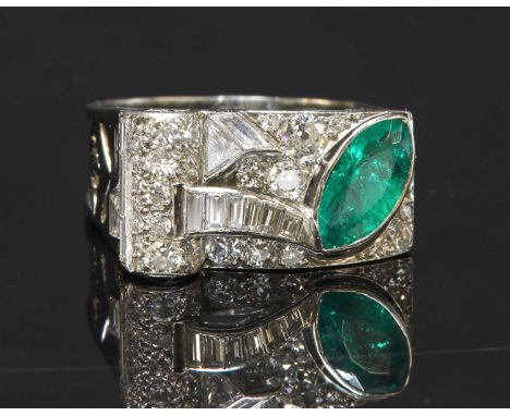 An odeonesque emerald and diamond cocktail ring, c.1935-1945, with a rectangular arched head with a scroll to one side. A mar