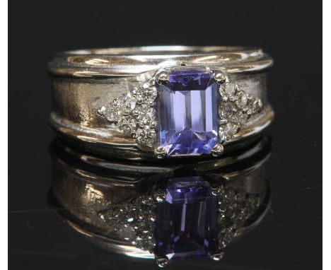A Continental tanzanite and diamond band ring, with an emerald cut tanzanite, four claw set to the centre. A triangular clust