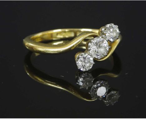 A gold three stone diamond crossover ring, with a line of three graduated old European cut diamonds, eight claw set to white 