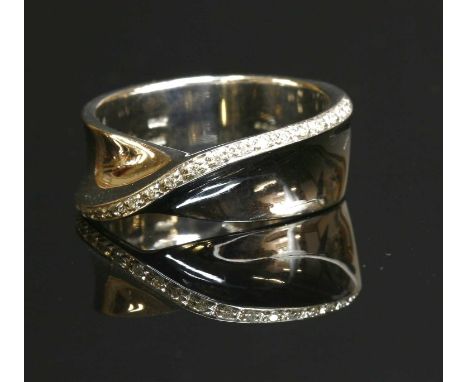 An 18ct white gold diamond set crossover band ring, with a flat section band 8.4mm wide. A diagonal row of brilliant cut diam