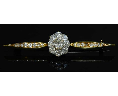 A diamond cluster bar brooch, with a central oval cluster of diamonds, with a cushion cut diamond, claw set to the centre, su