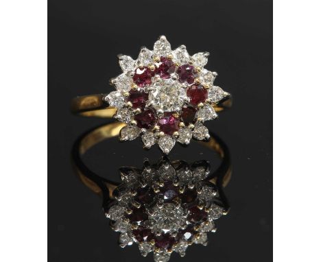 An 18ct gold diamond and ruby three-tier cluster ring, with a brilliant cut diamond, claw set to the centre. A border of circ