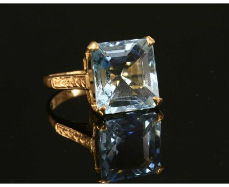 A single stone aquamarine ring, with a rectangular cut corner step cut aquamarine, four claw set at the cut corners to a coll