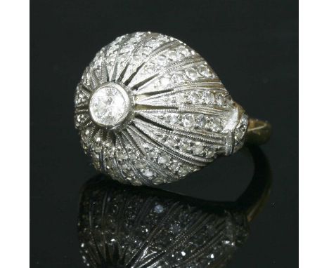 A Continental diamond set bombé ring, with a brilliant cut diamond rub set to the centre of the head. Pierced lines between r
