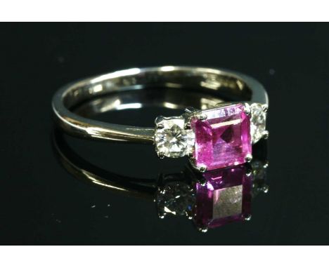 An 18ct white gold three stone pink sapphire and diamond ring, with a square, emerald cut pink sapphire, four claw set to the