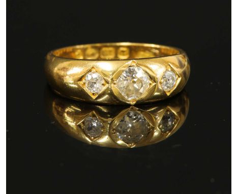 A gentlemen's 18ct gold three stone diamond ring, with a graduated old European cut and two cushion cut diamonds, all grain s