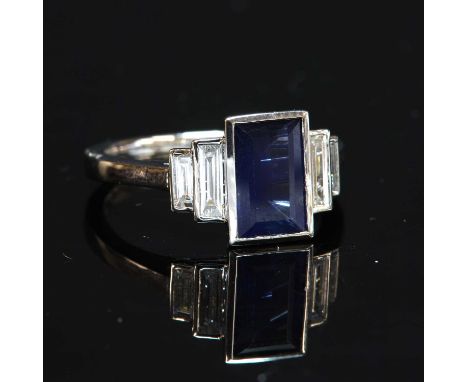 A platinum single stone sapphire ring, with stepped diamond shoulders, with a rectangular trap cut sapphire with a stated wei