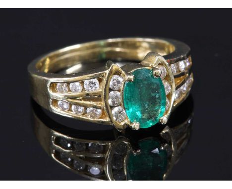 A gold emerald and diamond ring, with an oval mixed cut emerald, four claw set with a row of brilliant cut diamonds, bar set 