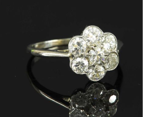 An Art Deco diamond set daisy cluster ring, with an old brilliant cut diamond, claw set to the centre. A border of larger old