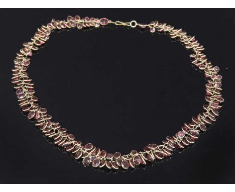 A gold graduated garnet garland necklace, with oval mixed cut garnets, spectacle set to a plain frame and all joined by one e