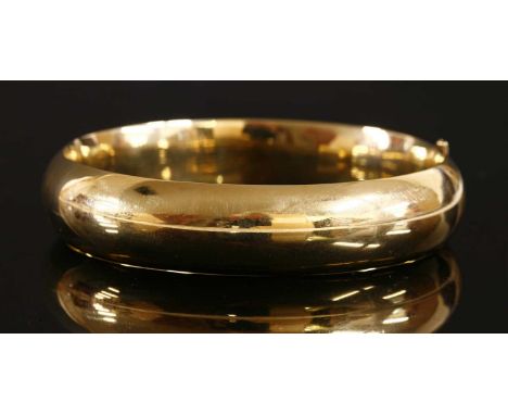 A hollow 'D' section hinged gold bangle, signed Succo, 'PAT 26898', with push piece and bar fitting. Tested as approximately 