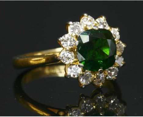 A demantoid garnet and diamond cushion shaped cluster ring, with a cushion-shaped mixed cut demantoid garnet, claw set to the