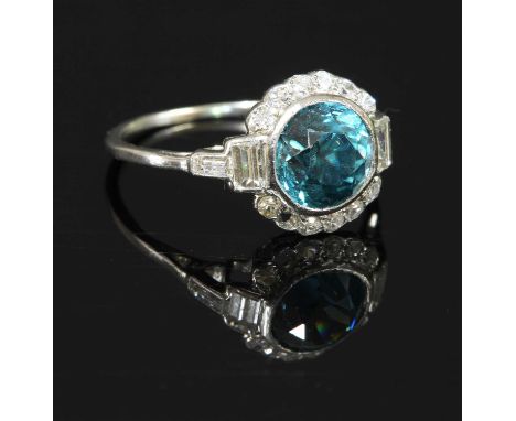 An Art Deco blue zircon and diamond daisy cluster ring, with a circular mixed cut blue zircon, rub set to the centre. A borde